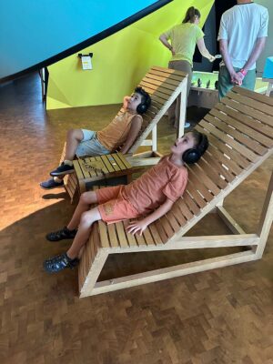 Schüler auf einer Holzbank mit Kopfhörer auf Entdeckungstour im Experimenta Heilbronn